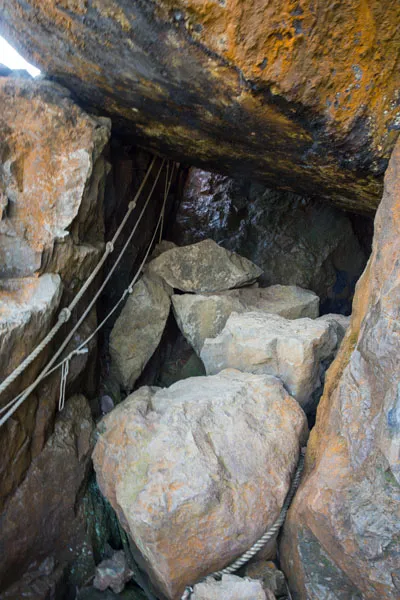 A pile of large rocks pictured from the mouth of a cave, which serve as stepping stones to the top.