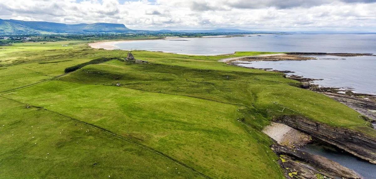 a green field with a body of water and a rocky beach