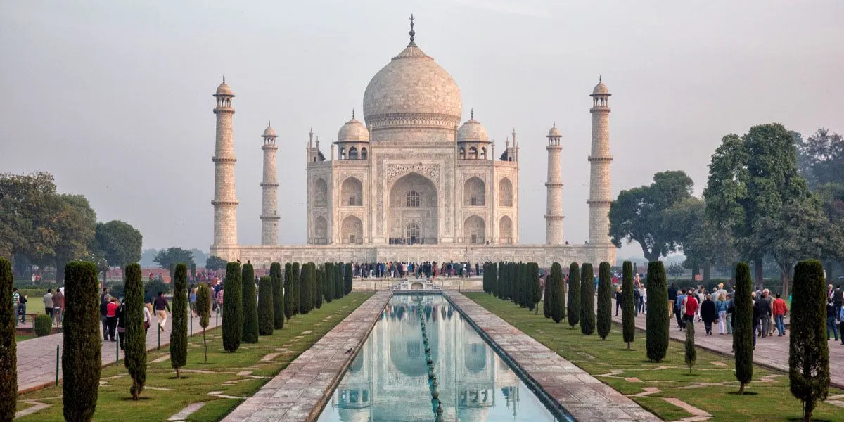 a large building with a pool of water and trees with Taj Mahal in the background